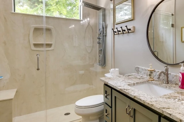 bathroom featuring vanity, a shower with door, toilet, and plenty of natural light