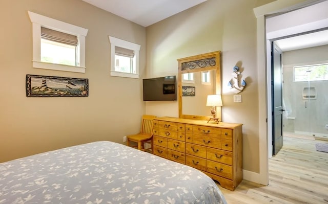 bedroom with multiple windows, ensuite bathroom, and light wood-type flooring