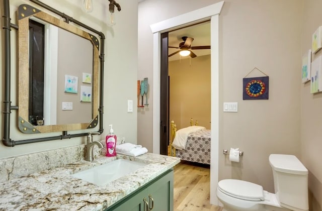 bathroom featuring ceiling fan, vanity, wood-type flooring, and toilet