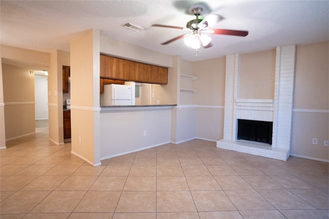 kitchen featuring white refrigerator, a brick fireplace, ceiling fan, a textured ceiling, and light tile patterned flooring