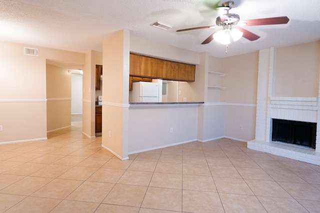 kitchen with ceiling fan, light tile patterned floors, a fireplace, a textured ceiling, and white fridge