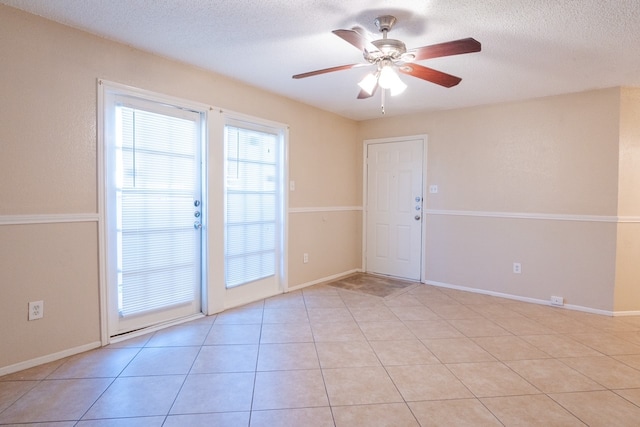 spare room with ceiling fan, light tile patterned floors, and a textured ceiling