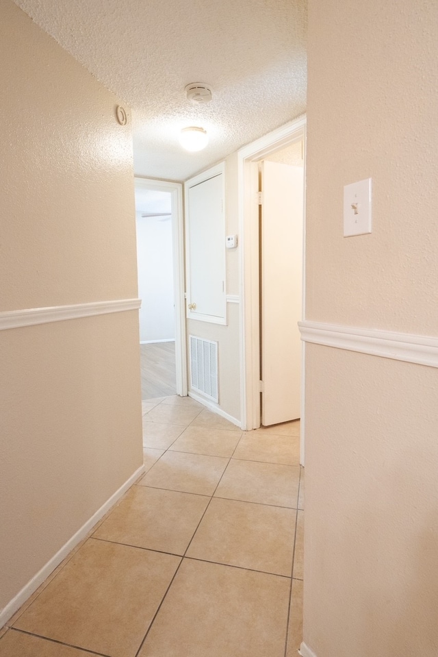 hallway with light tile patterned floors and a textured ceiling