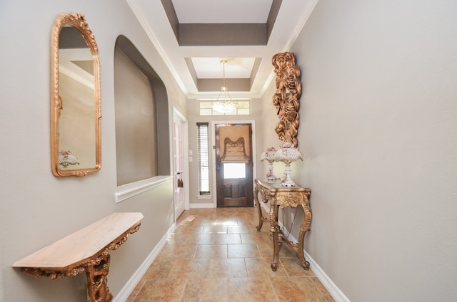 foyer entrance with a raised ceiling and crown molding