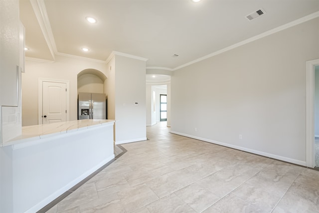 interior space with kitchen peninsula, light stone countertops, ornamental molding, and stainless steel refrigerator with ice dispenser