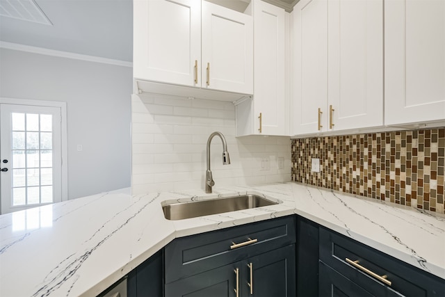 kitchen featuring backsplash, light stone counters, sink, and white cabinets