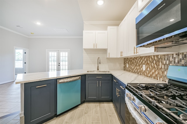 kitchen featuring light stone countertops, white cabinetry, stainless steel appliances, backsplash, and kitchen peninsula