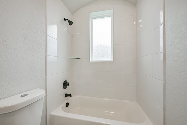 bathroom with tiled shower / bath combo and toilet