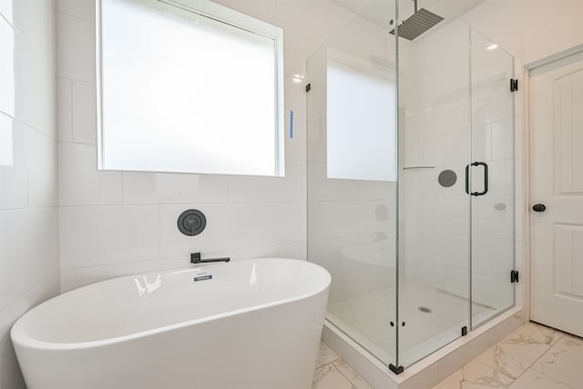 bathroom featuring shower with separate bathtub and tile walls