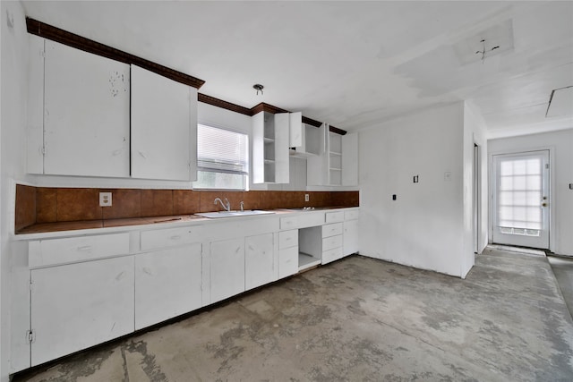 kitchen with white cabinets, concrete floors, and sink