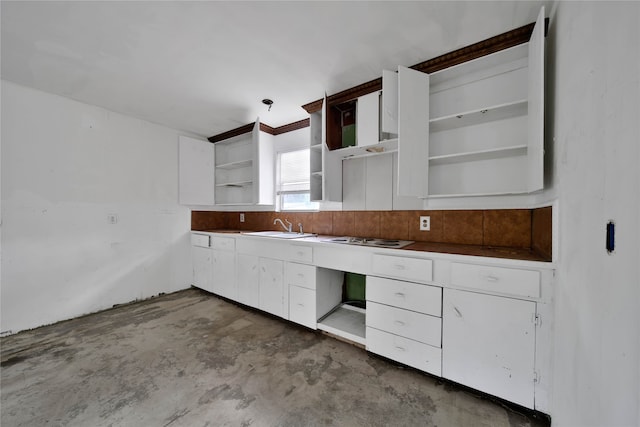 kitchen with white cabinetry, sink, concrete floors, and white stovetop