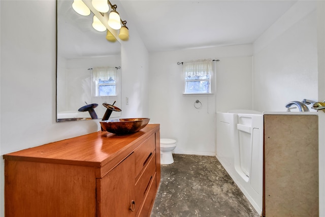 bathroom featuring plenty of natural light, vanity, concrete flooring, and toilet