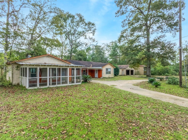 ranch-style home featuring a sunroom and a front lawn