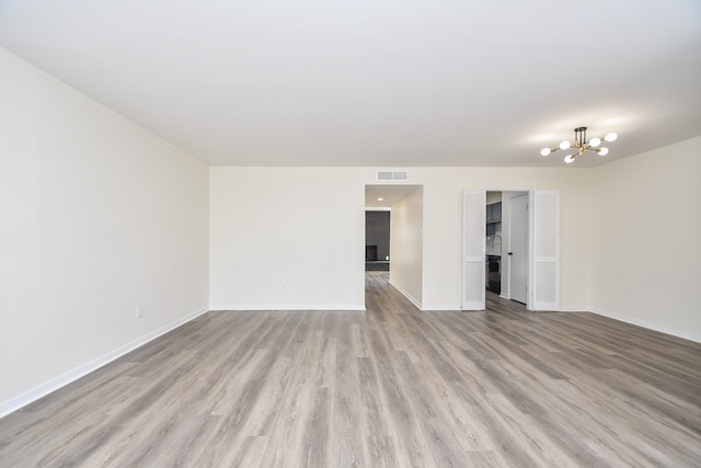 empty room with a chandelier and light hardwood / wood-style flooring