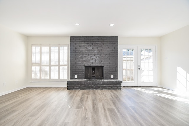 unfurnished living room featuring a fireplace, french doors, and light hardwood / wood-style floors