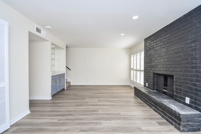 unfurnished living room featuring a fireplace and light hardwood / wood-style floors