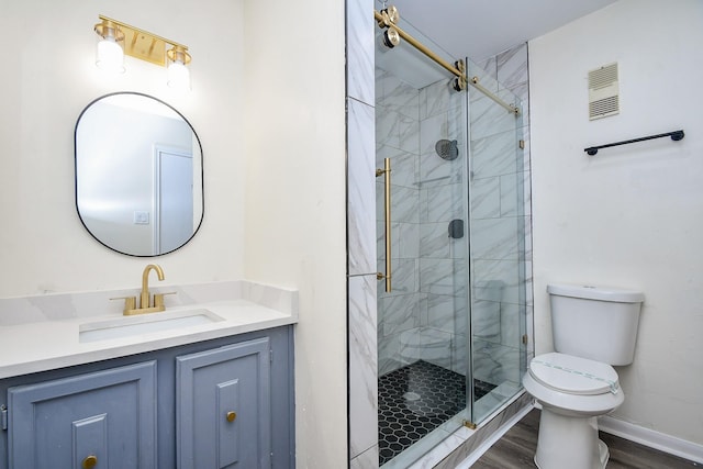 bathroom featuring vanity, hardwood / wood-style flooring, a shower with door, and toilet