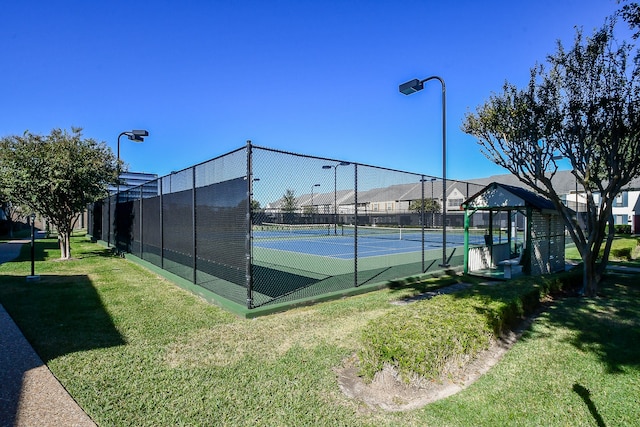 view of tennis court featuring a lawn