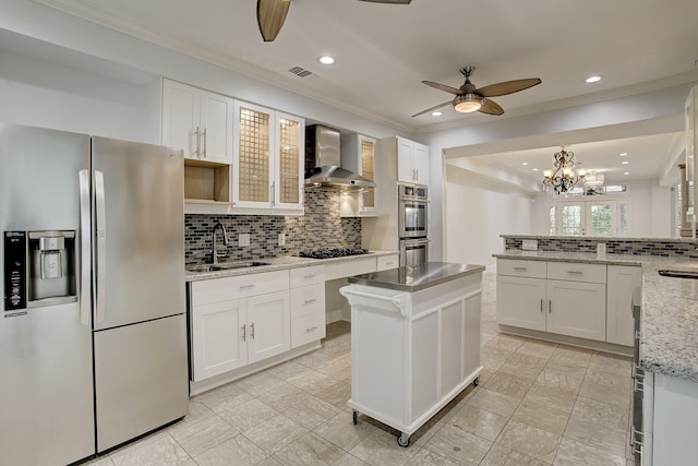 kitchen featuring a center island, sink, stainless steel appliances, wall chimney range hood, and white cabinets