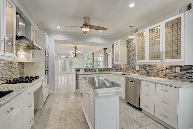 kitchen with wall chimney exhaust hood, stainless steel appliances, decorative light fixtures, decorative backsplash, and white cabinets