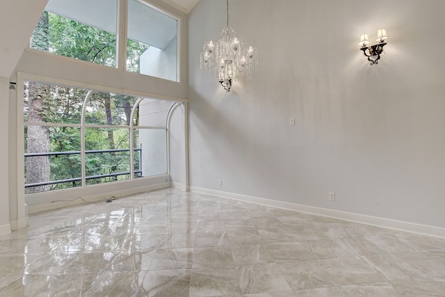 empty room with a wealth of natural light, a high ceiling, and an inviting chandelier