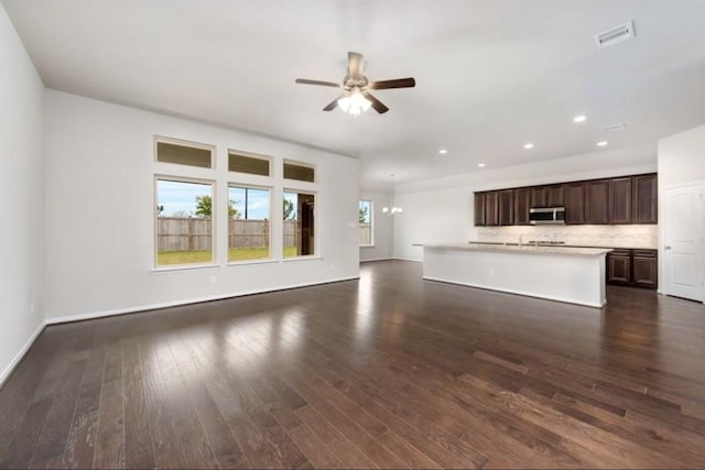 unfurnished living room with dark hardwood / wood-style flooring and ceiling fan with notable chandelier