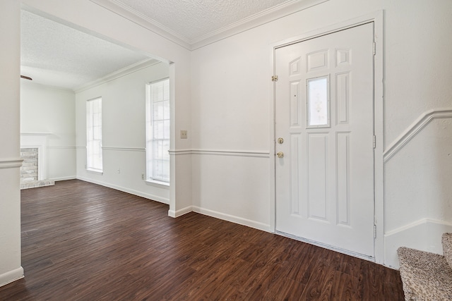 entrance foyer featuring a textured ceiling, dark hardwood / wood-style floors, a brick fireplace, and ornamental molding