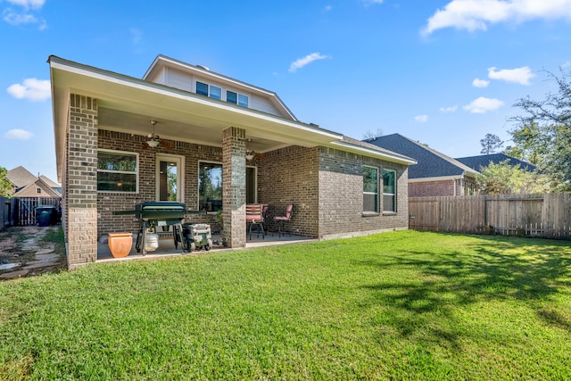 rear view of house with ceiling fan, a patio area, and a lawn