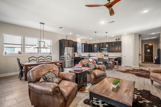 living room featuring ceiling fan with notable chandelier