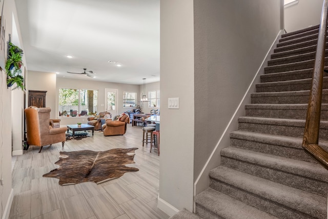 stairway with ceiling fan with notable chandelier