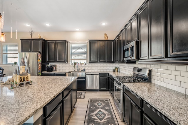 kitchen with light stone countertops, sink, backsplash, and stainless steel appliances