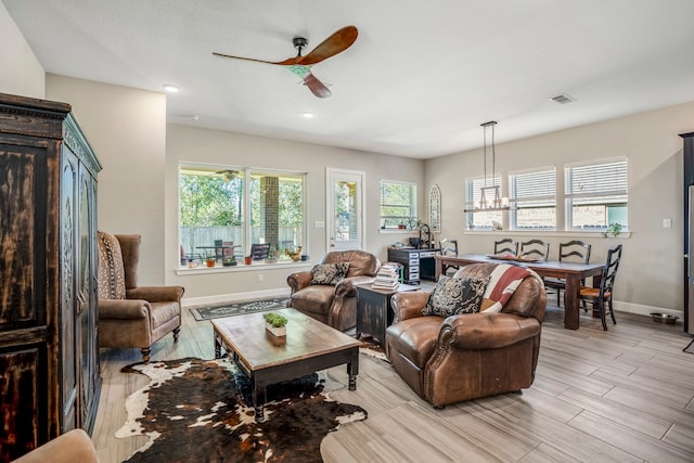 living room with ceiling fan with notable chandelier and light wood-type flooring