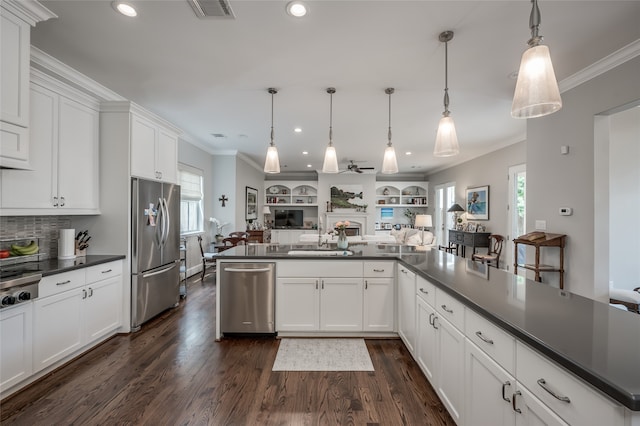 kitchen with dark hardwood / wood-style flooring, white cabinetry, hanging light fixtures, and appliances with stainless steel finishes