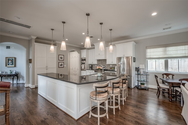 kitchen featuring white cabinets, a center island with sink, hanging light fixtures, and appliances with stainless steel finishes