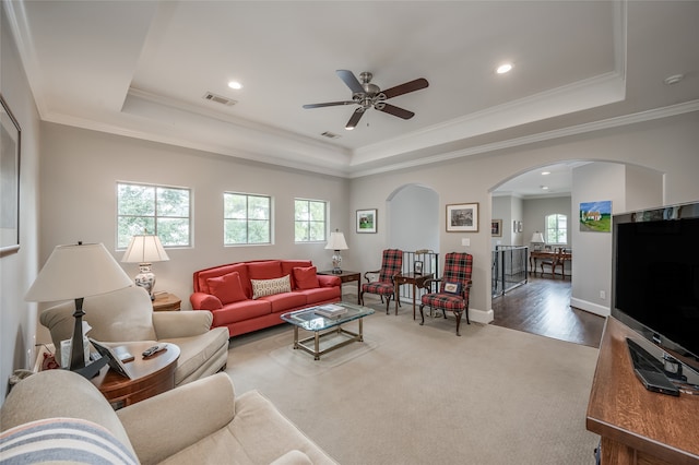 living room featuring hardwood / wood-style flooring, a raised ceiling, ceiling fan, and crown molding