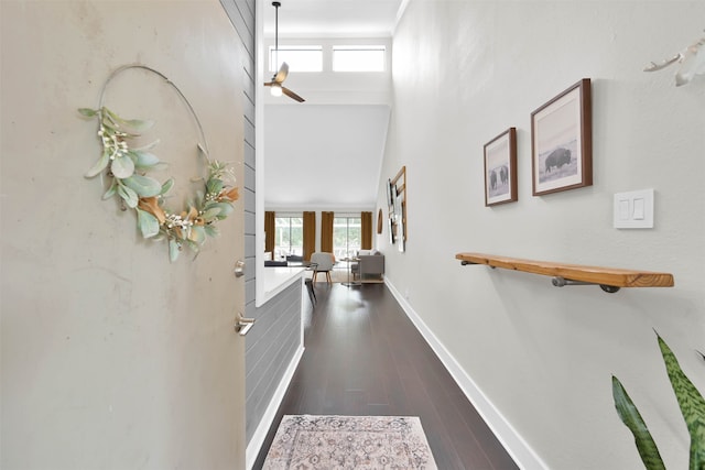 corridor with a towering ceiling and dark hardwood / wood-style flooring