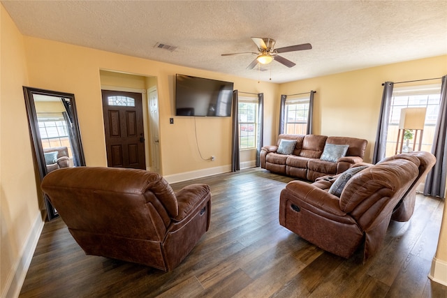 living room with a textured ceiling, ceiling fan, and dark hardwood / wood-style floors