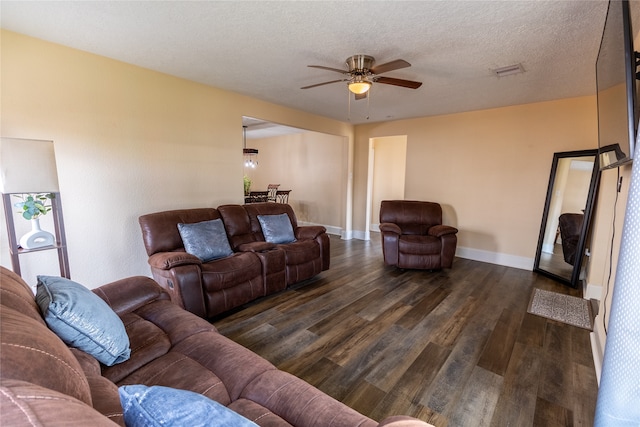 living room featuring a textured ceiling, ceiling fan, and dark wood-type flooring