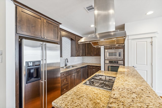 kitchen with sink, appliances with stainless steel finishes, dark brown cabinets, light stone counters, and island exhaust hood