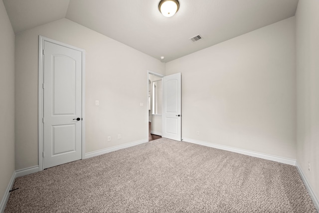 unfurnished bedroom with carpet flooring and vaulted ceiling