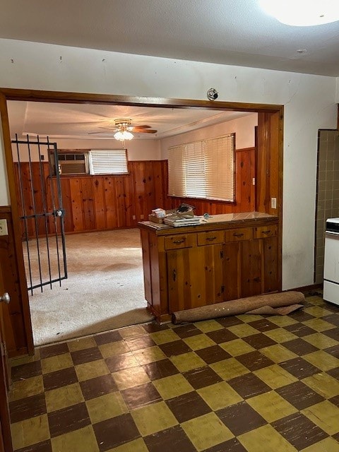 kitchen featuring wooden walls and dark colored carpet