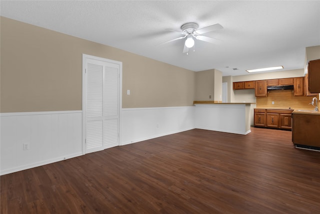 unfurnished living room with ceiling fan, sink, dark wood-type flooring, and a textured ceiling