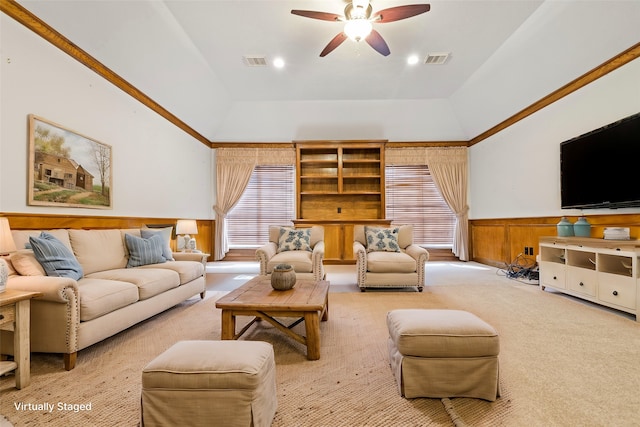 carpeted living room featuring ceiling fan, wood walls, crown molding, and vaulted ceiling