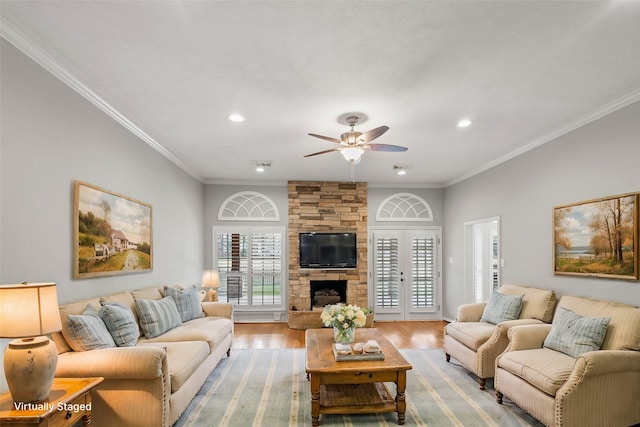 living room with hardwood / wood-style flooring, ceiling fan, a fireplace, and crown molding