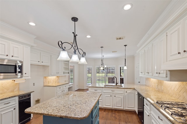 kitchen with appliances with stainless steel finishes, sink, decorative light fixtures, white cabinets, and a kitchen island