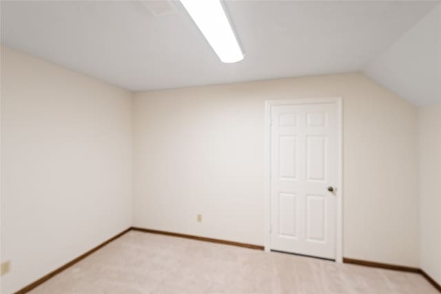 additional living space featuring light colored carpet and vaulted ceiling