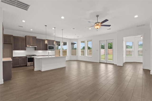 kitchen featuring a kitchen island with sink, ceiling fan, appliances with stainless steel finishes, decorative light fixtures, and dark brown cabinets