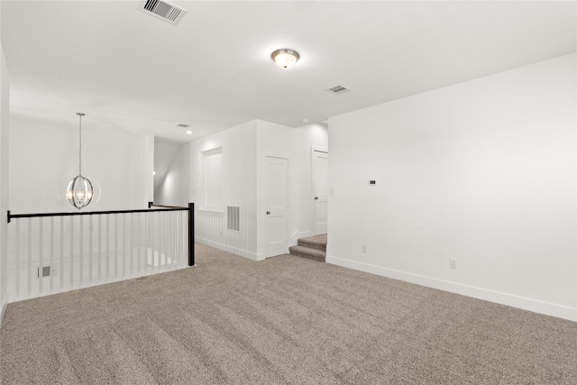 spare room featuring carpet flooring and a notable chandelier