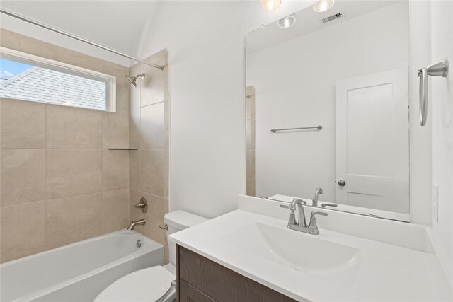 full bathroom featuring vanity, tiled shower / bath combo, and toilet