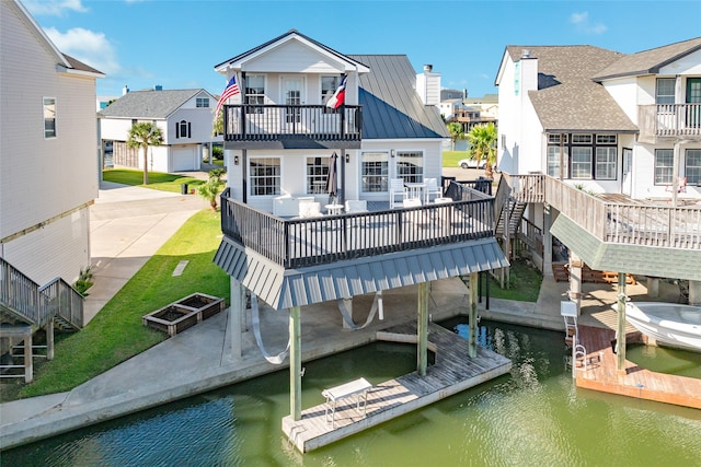 back of house featuring a lawn, a deck with water view, and a patio